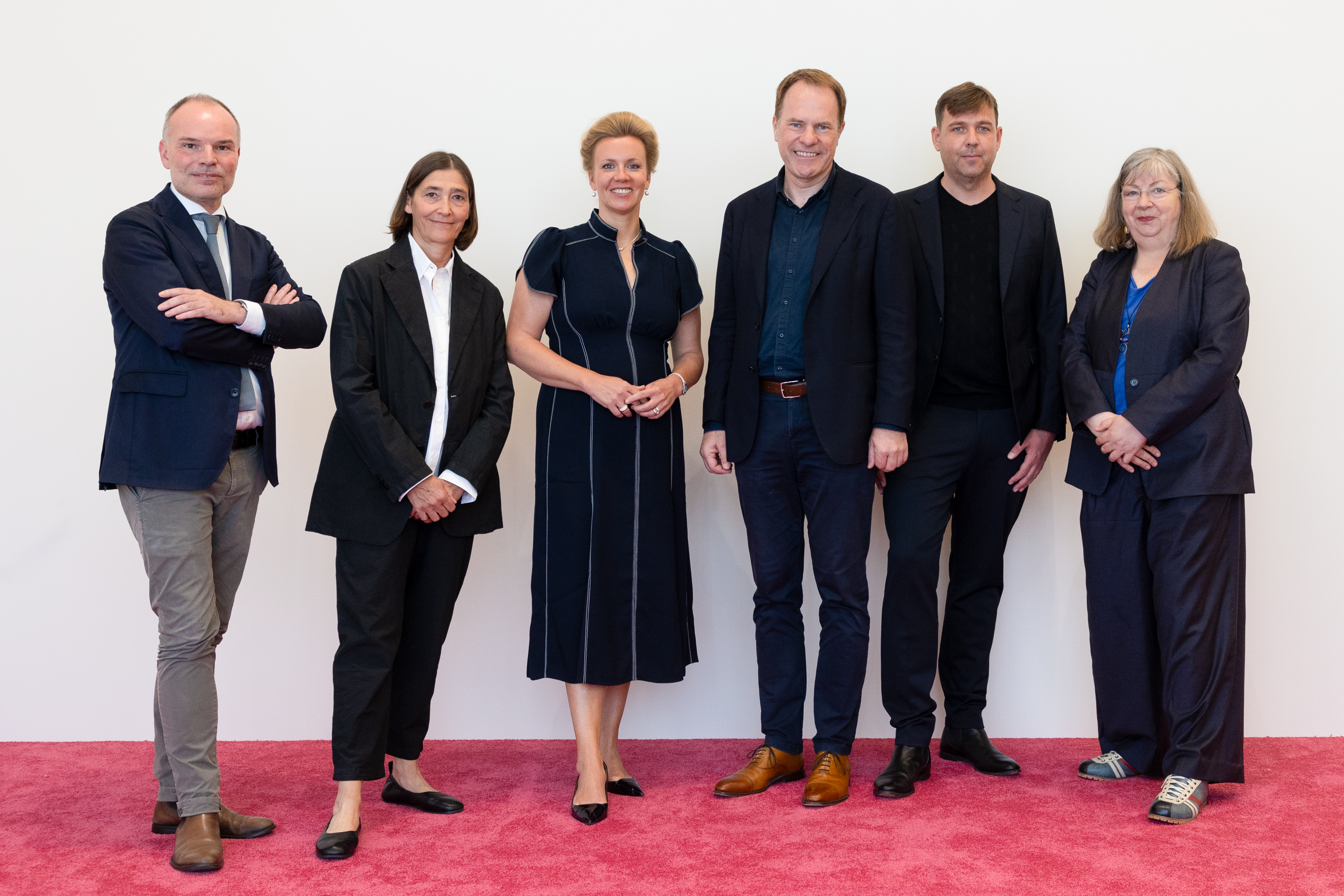Sechser-Gruppe auf rotem Teppich vor weißer Wand