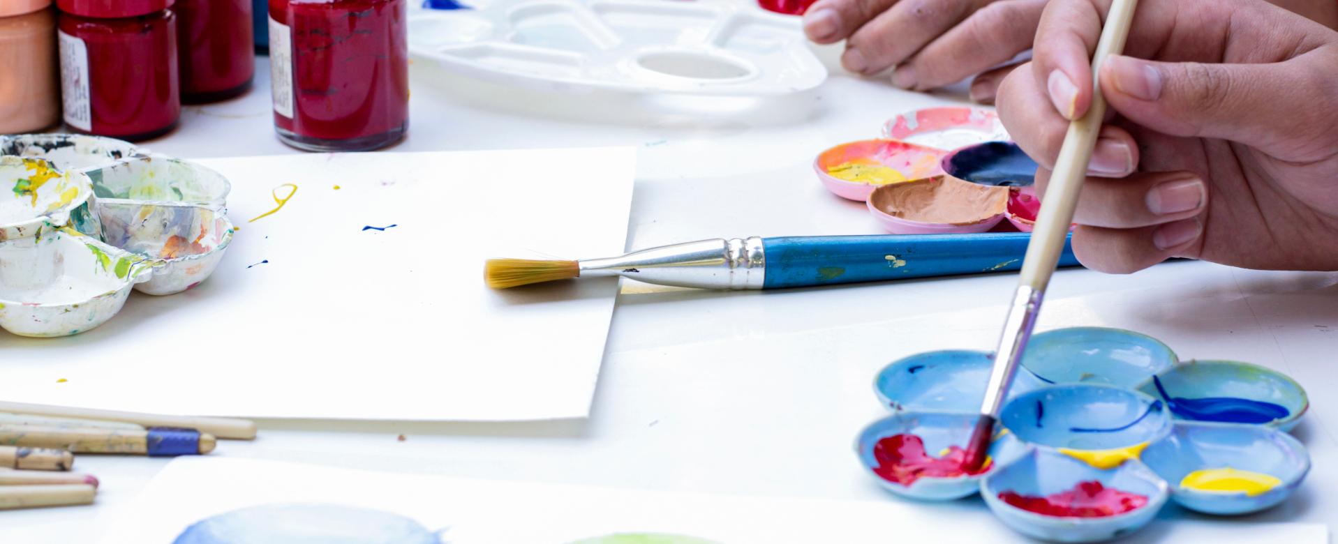Personen malen mit Pinsel und Farben auf Papier