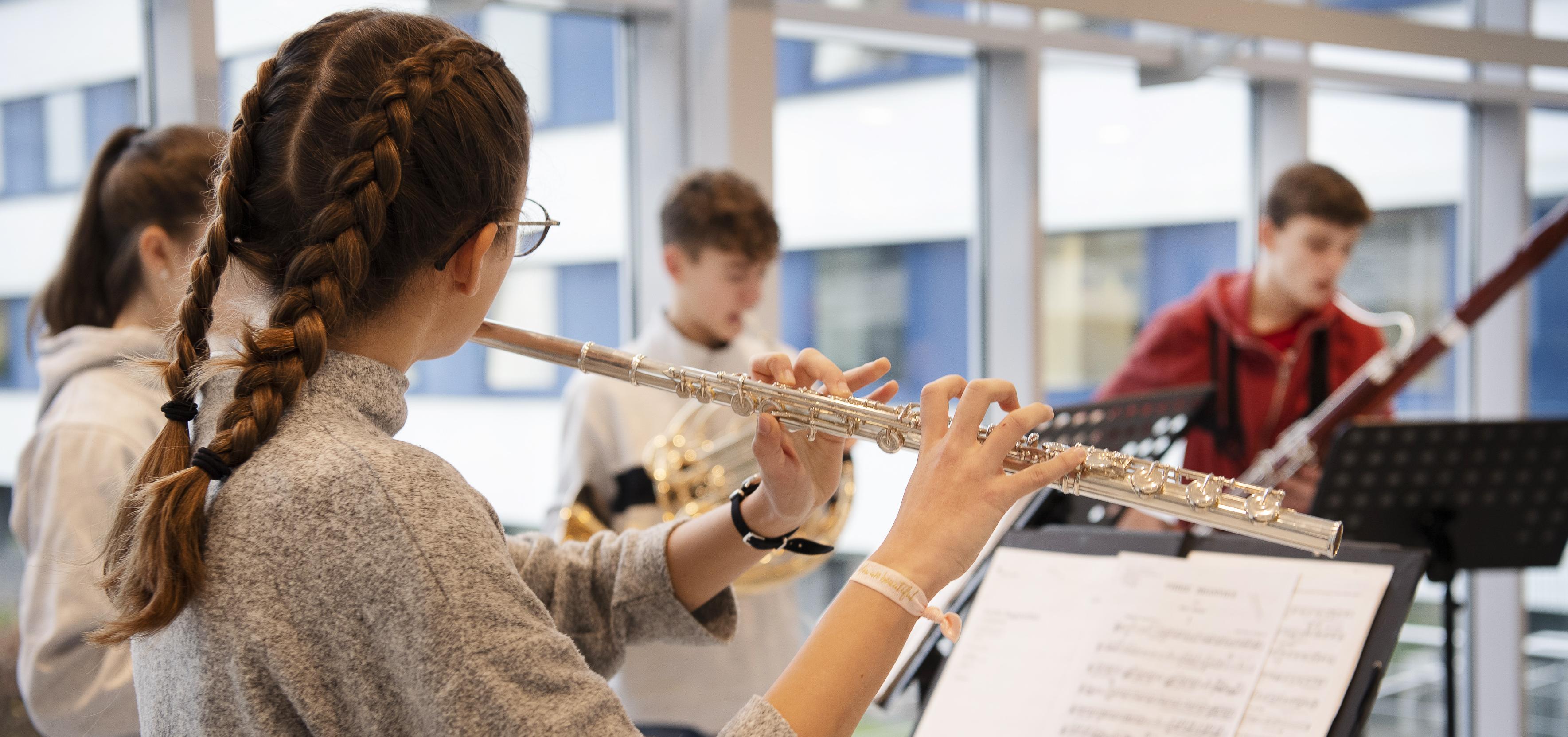 Querflötenspielerin im Vordergrund mit weiteren Instrumentalisten im Hintergrund
