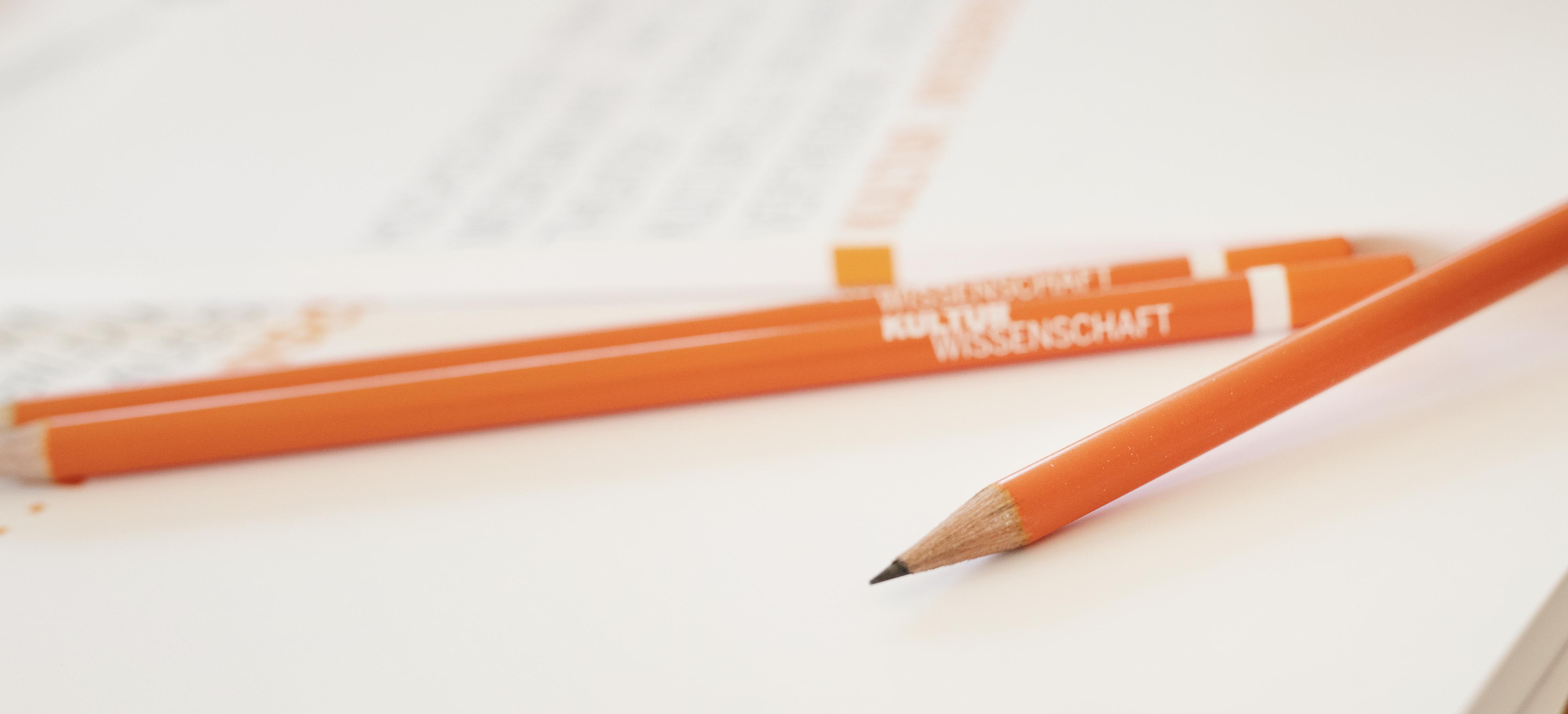 Orange Stifte liegen auf Papier