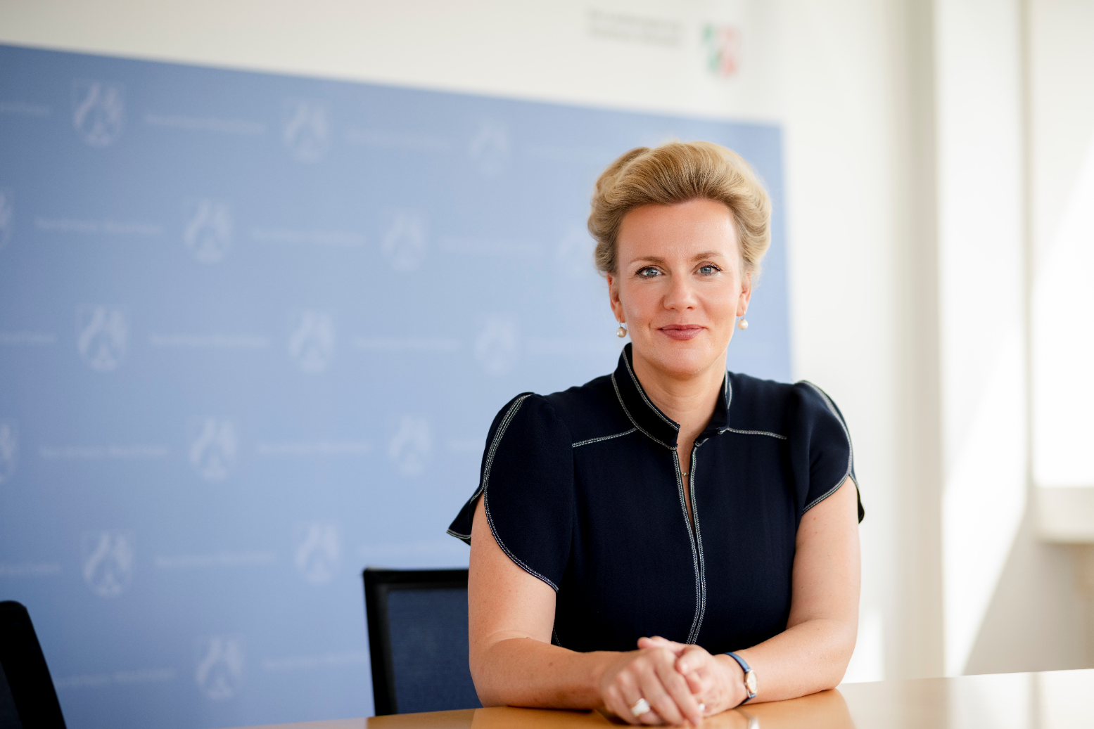 Ministerin Ina Brandes MdL sitzend vor einer Pressewand