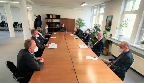 Teilnehmer mit Masken an einem Sitzungstisch