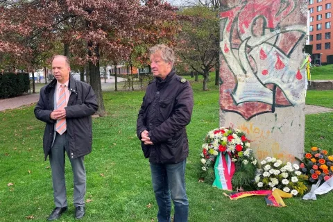 Zwei Männer vor Gedenkstein mit Kränzen
