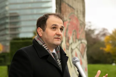 Redner mit Mikrofon vor Gedenkstein