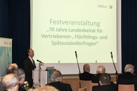 Redner an Pult vor Leinwand