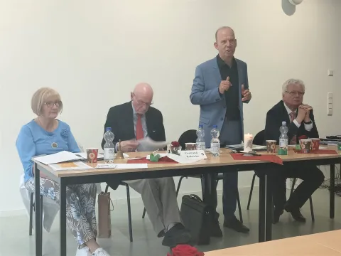 4 Personen an zwei Tischen, einer stehend