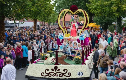 Blumengeschmückter Wagen inmitten zuschauender Menge