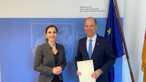 Zu sehen sind nebeneinander stehend Gonca Türkeli-Dehnert, Staatssekretärin im Ministerium für Kultur und Wissenschaft, und Heiko Hendriks, Beauftragter der Landesregierung für die Belange von deutschen Heimatvertriebenen, Aussiedlern und Spätaussiedlern. 