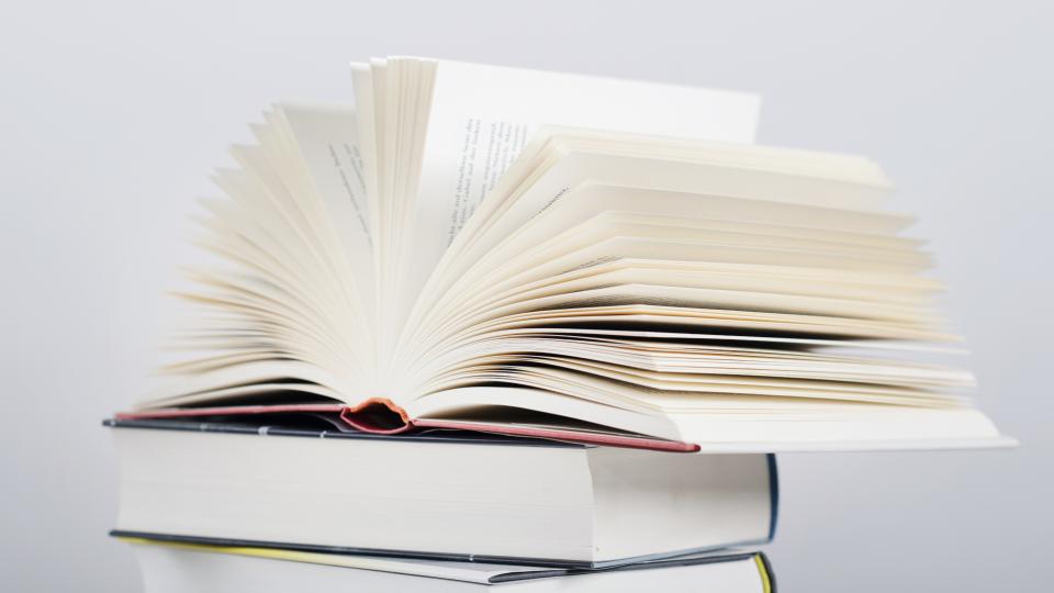 Aufgeschlagenes Buch auf Bücherstapel