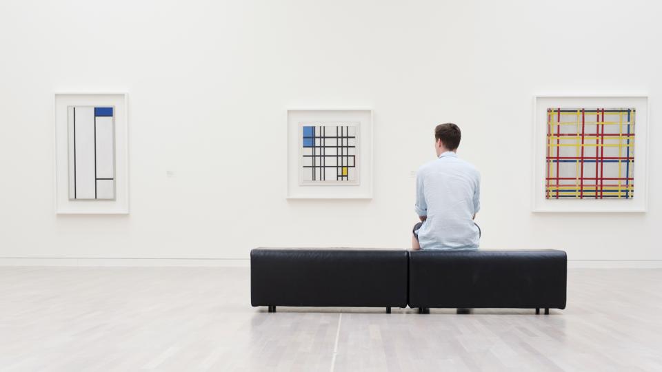 Mann sitzt auf Bank vor einer Ausstellung von Bildern