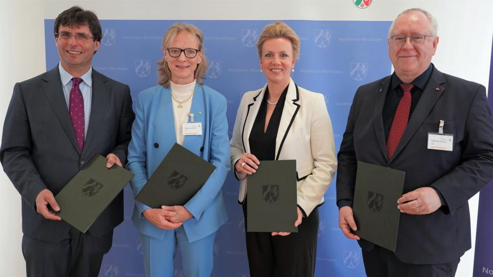 Zwei Frauen und zwei Männer vor blauer Stellwand
