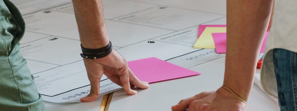 Zwei Personen an einem Tisch diskutieren Papiere, die vor ihnen liegen