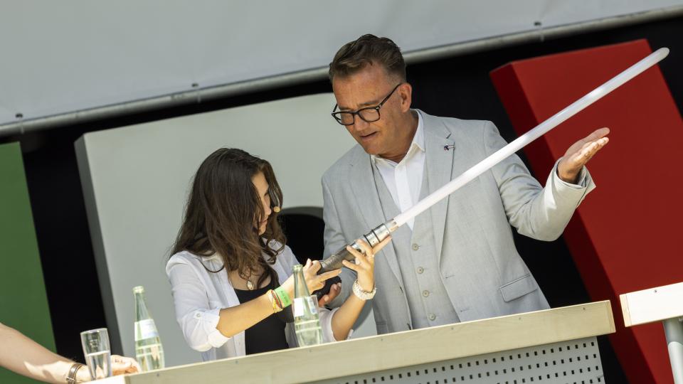 Schülerin Amelie mit selbstgebautem Lichtschwert auf Bühne