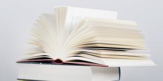 Aufgeschlagenes Buch auf Bücherstapel