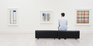 Mann sitzt auf Bank vor einer Ausstellung von Bildern