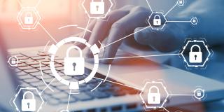 Hand an Laptoptastatur, vordergründig ein Schloss-Symbol