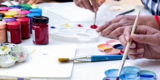Personen malen mit Pinsel und Farben auf Papier