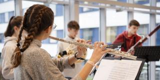 Querflötenspielerin im Vordergrund mit weiteren Instrumentalisten im Hintergrund