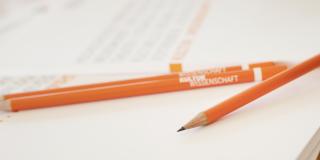 Orange Stifte liegen auf Papier