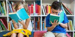 Ein Mädchen und ein Junge lesen ein Buch in einer Bibliothek