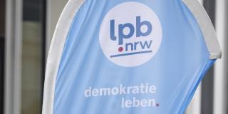 Frau vor der fokussierten Beachflag der Landeszentrale für politische Bildung