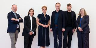 Sechser-Gruppe auf rotem Teppich vor weißer Wand