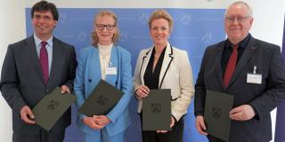 Zwei Frauen und zwei Männer vor blauer Stellwand