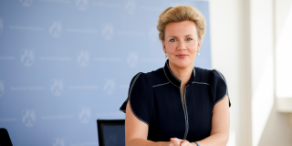 Ministerin Ina Brandes MdL sitzend vor einer Pressewand