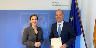 Zu sehen sind nebeneinander stehend Gonca Türkeli-Dehnert, Staatssekretärin im Ministerium für Kultur und Wissenschaft, und Heiko Hendriks, Beauftragter der Landesregierung für die Belange von deutschen Heimatvertriebenen, Aussiedlern und Spätaussiedlern. 