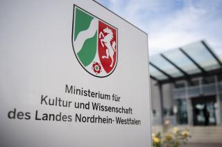 Schild vor dem Eingang des Ministeriums mit NRW-Landeswappen und der Aufschrift "Ministerium für Kultur und Wissenschaft des Landes Nordrhein-Westfalen"