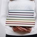 Eine Frau trägt einen Stapel Bücher