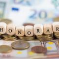 Sieben Würfel mit Buchstaben, die das Wort "Honorar" bilden. Im Hintergrund sieht man Geld.