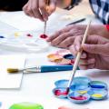 Personen malen mit Pinsel und Farben auf Papier