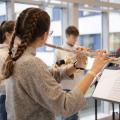 Querflötenspielerin im Vordergrund mit weiteren Instrumentalisten im Hintergrund