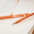 Orange Stifte liegen auf Papier