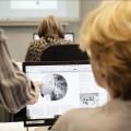 Frau sitzt vor dem Computer und kriegt etwas gezeigt